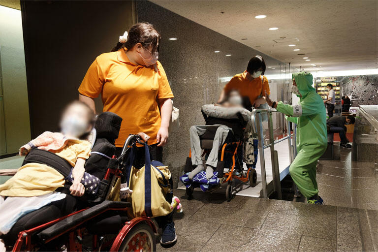 ホールに来場するお客様。会場には車いすで移動できるスロープを設置。カエルの格好をしたスタッフが出迎え、優しく誘導する